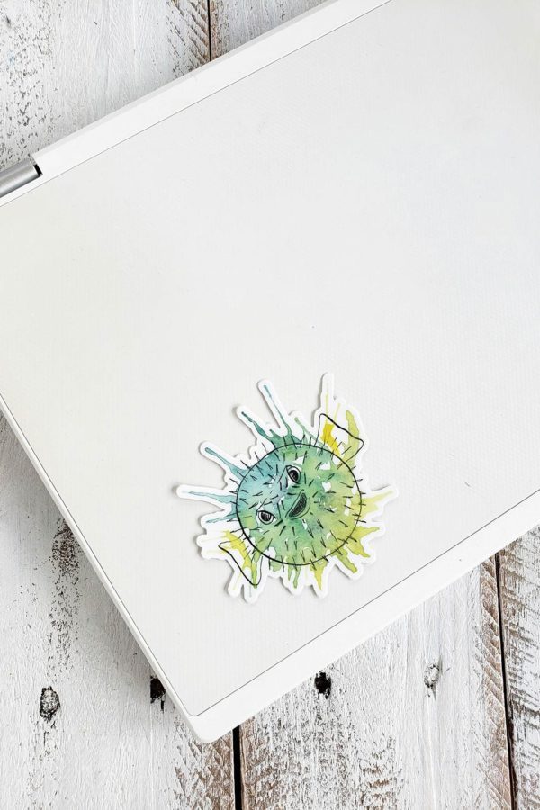 a puffer fish sticker on a laptop