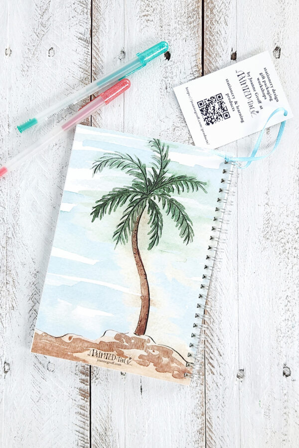 a watercolor palm tree is on the back of a notebook